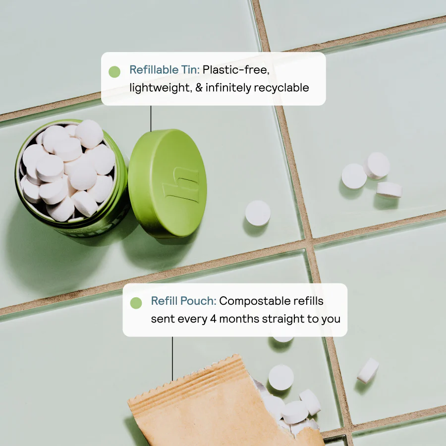 Green tin with white tablets on a tiled surface.