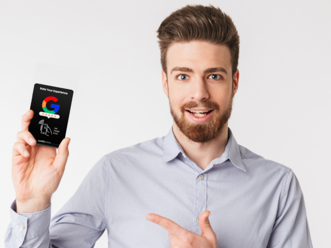Man in a shirt holding and pointing at a card with a logo.