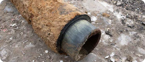 Rusty, corroded pipe lying on the ground.
