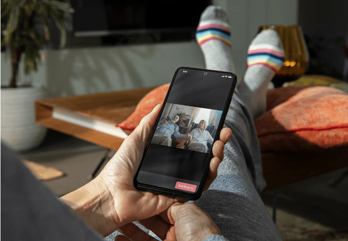 Person holding a smartphone showing a video call with two people on screen.