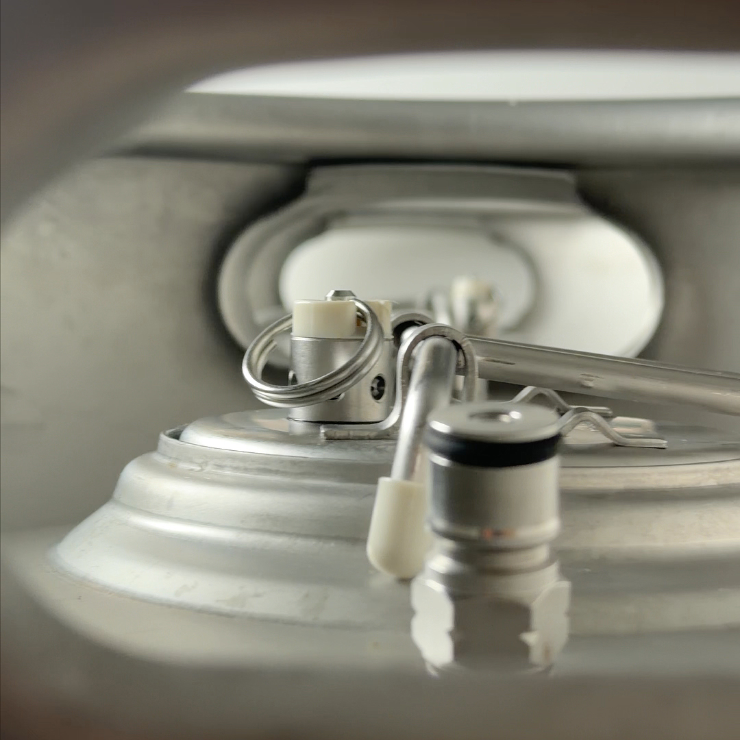 A close-up view of the pressure relief valve and fittings on top of a stainless steel keg.
