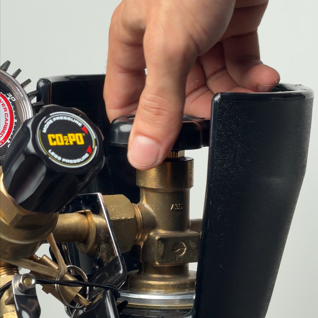 A close-up of a hand turning the black valve on top of a CO2 tank.