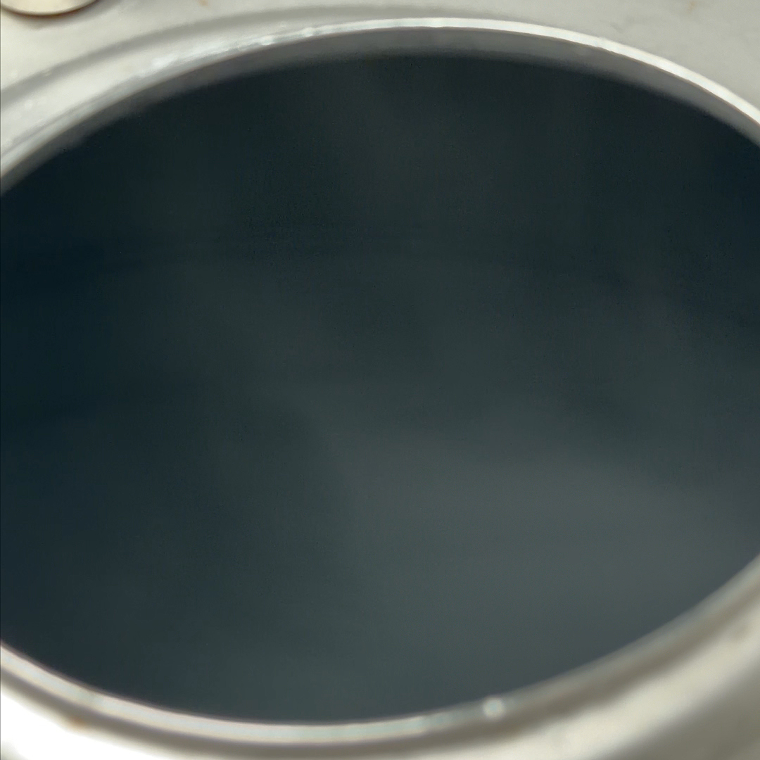 A close-up shot looking down into the dark, circular opening of a metal container.