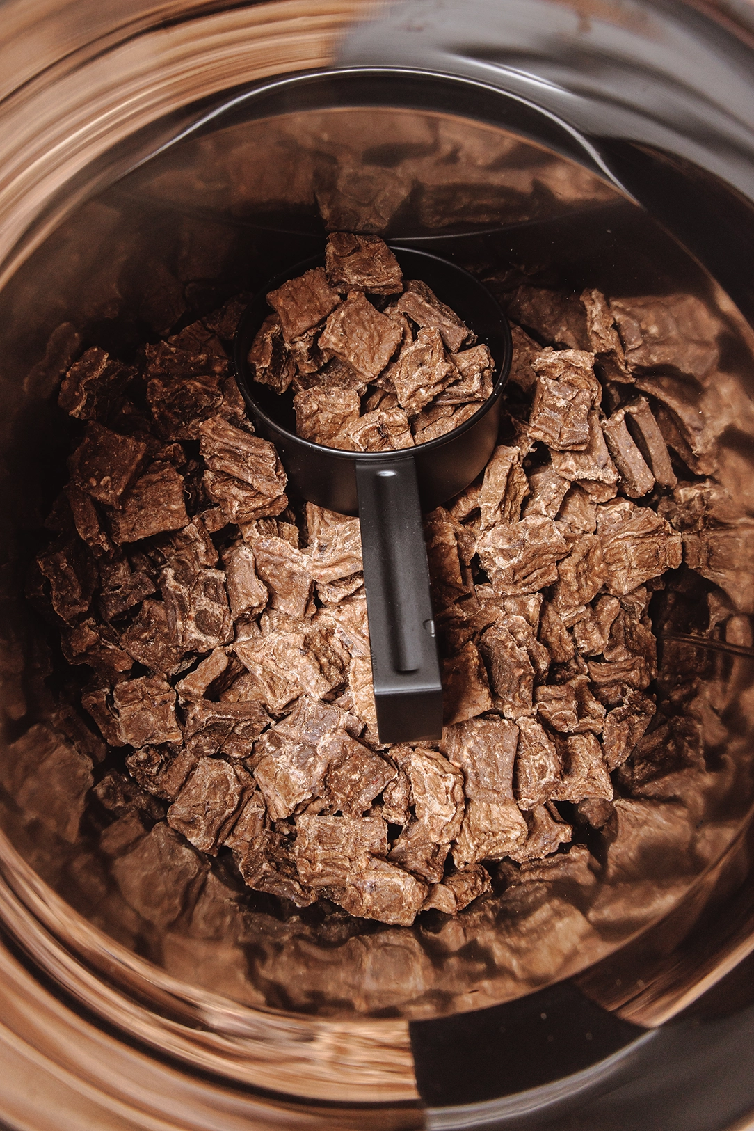 Close up of brown nuggets Eureka dog food, in storage container with scoop.