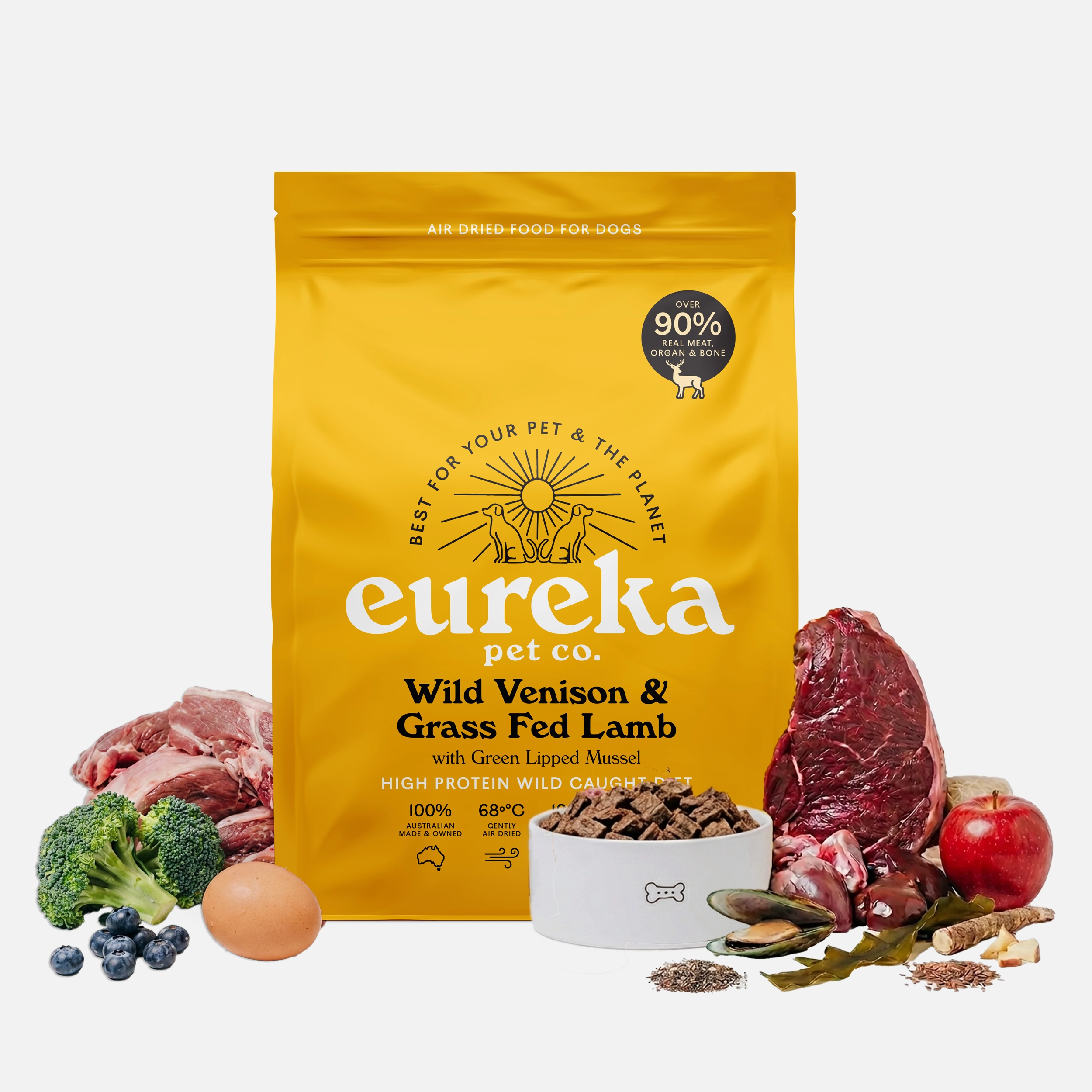 Eureka Pet Co. Wild Venison & Grass Fed Lamb air-dried dog food 1.8kg bag surrounded by fresh whole ingredients including venison, grass fed lamb, broccoli, apple, blueberries, egg and green lipped mussel with a bowl of food pieces.