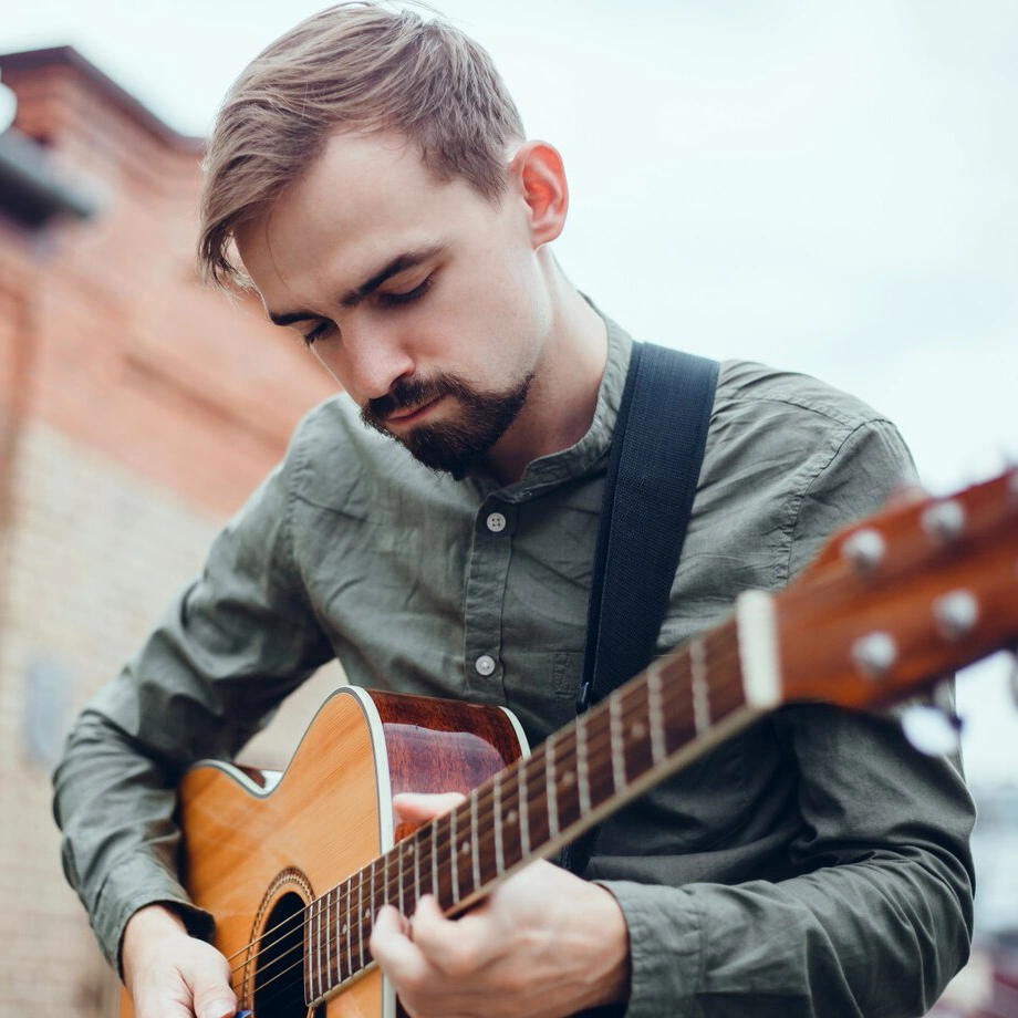 Man playing an acoustic guitar outdoors.
