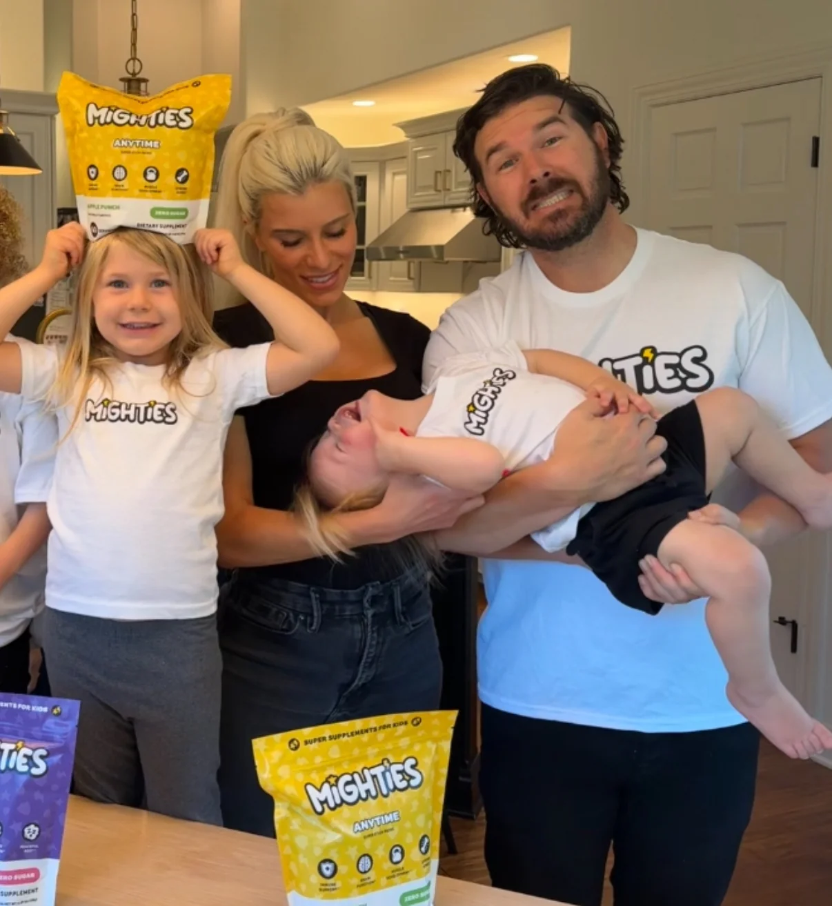Family in kitchen with children holding Mighties supplement bags.