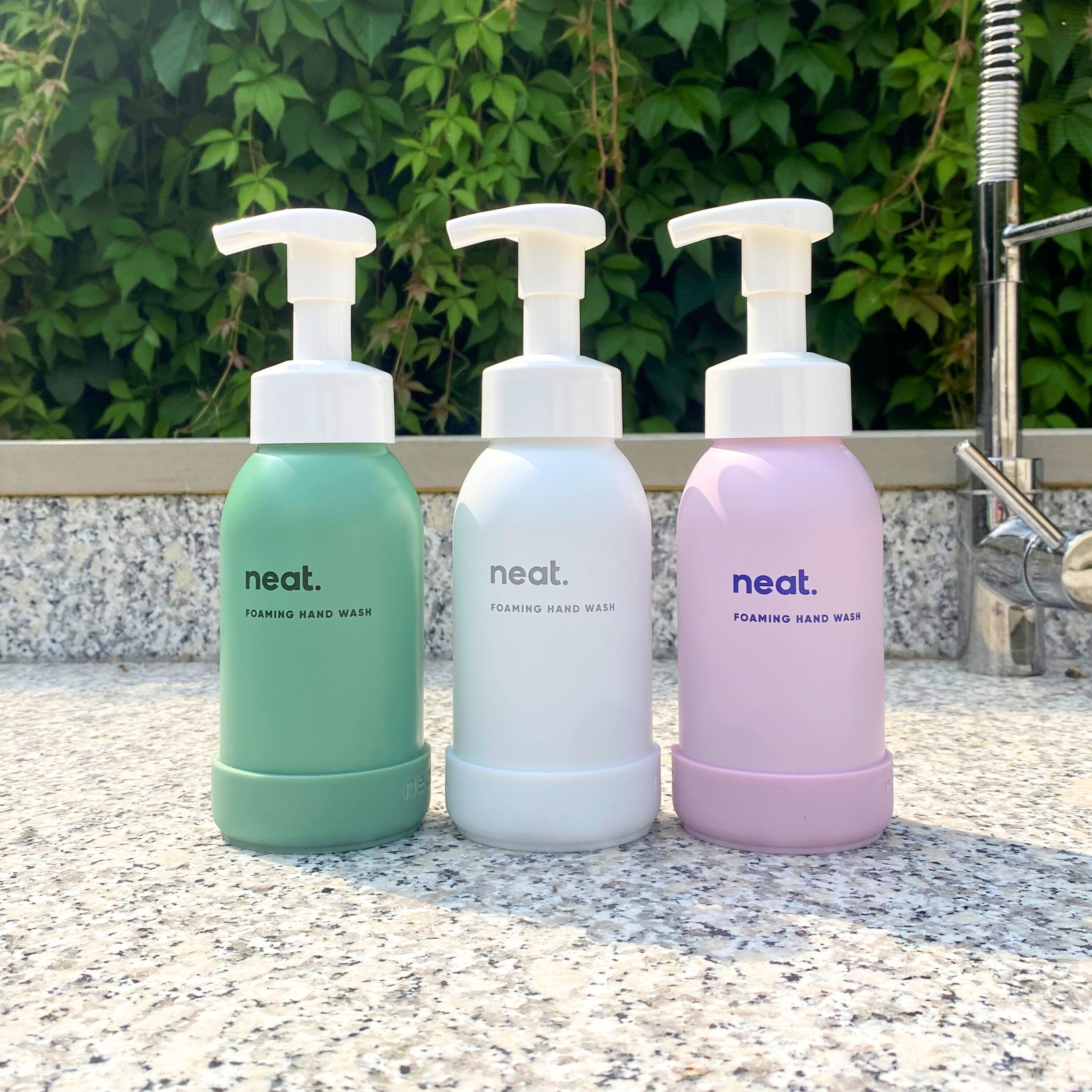 Three bottles of foaming hand wash on a granite countertop.