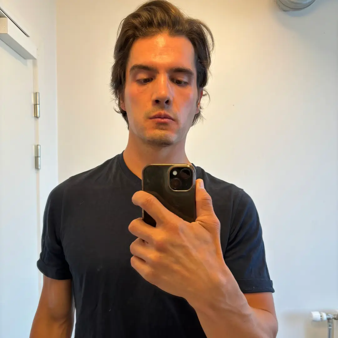 Person in a black shirt taking a mirror selfie with a smartphone.