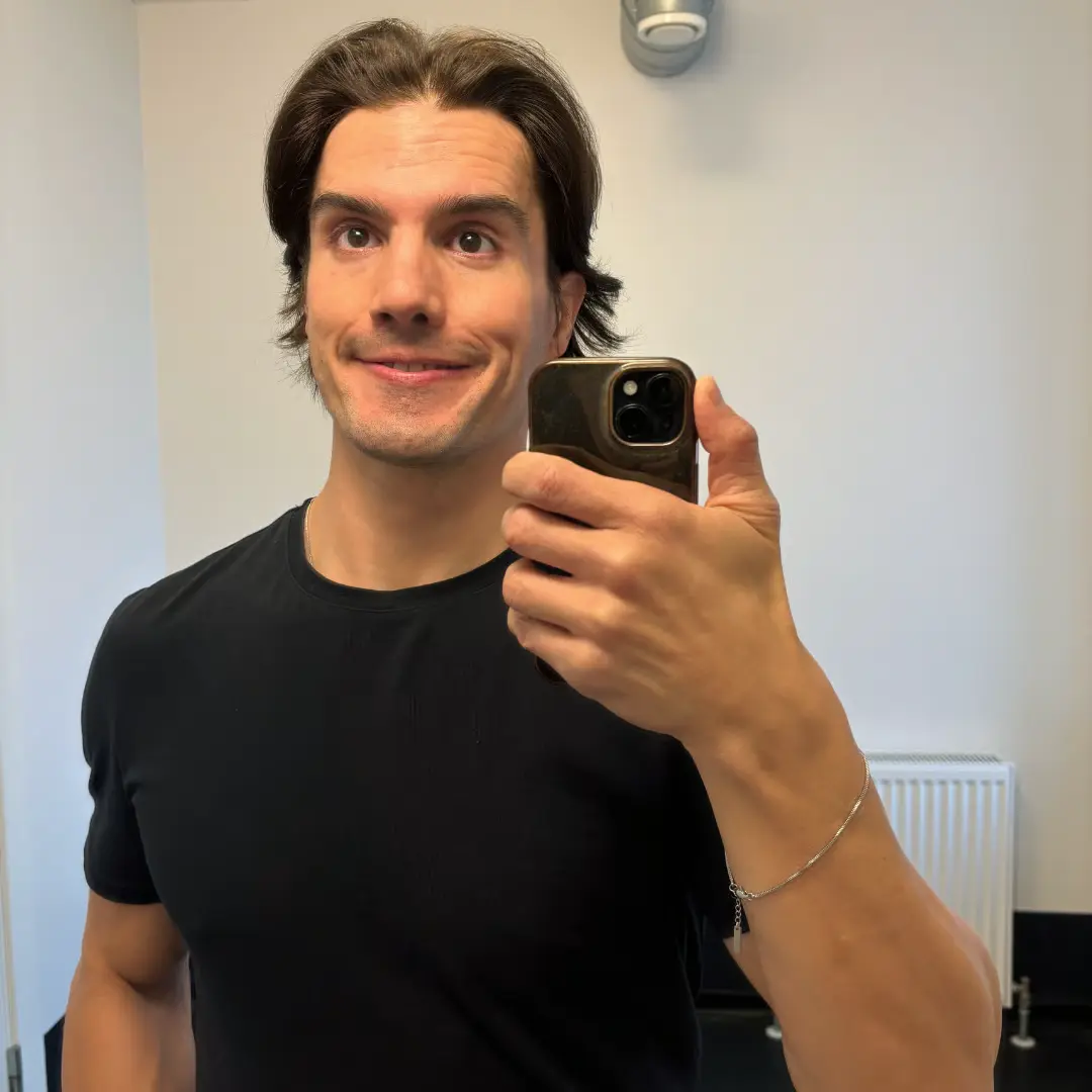 Person taking a selfie in a mirror, wearing a black shirt and holding a phone.
