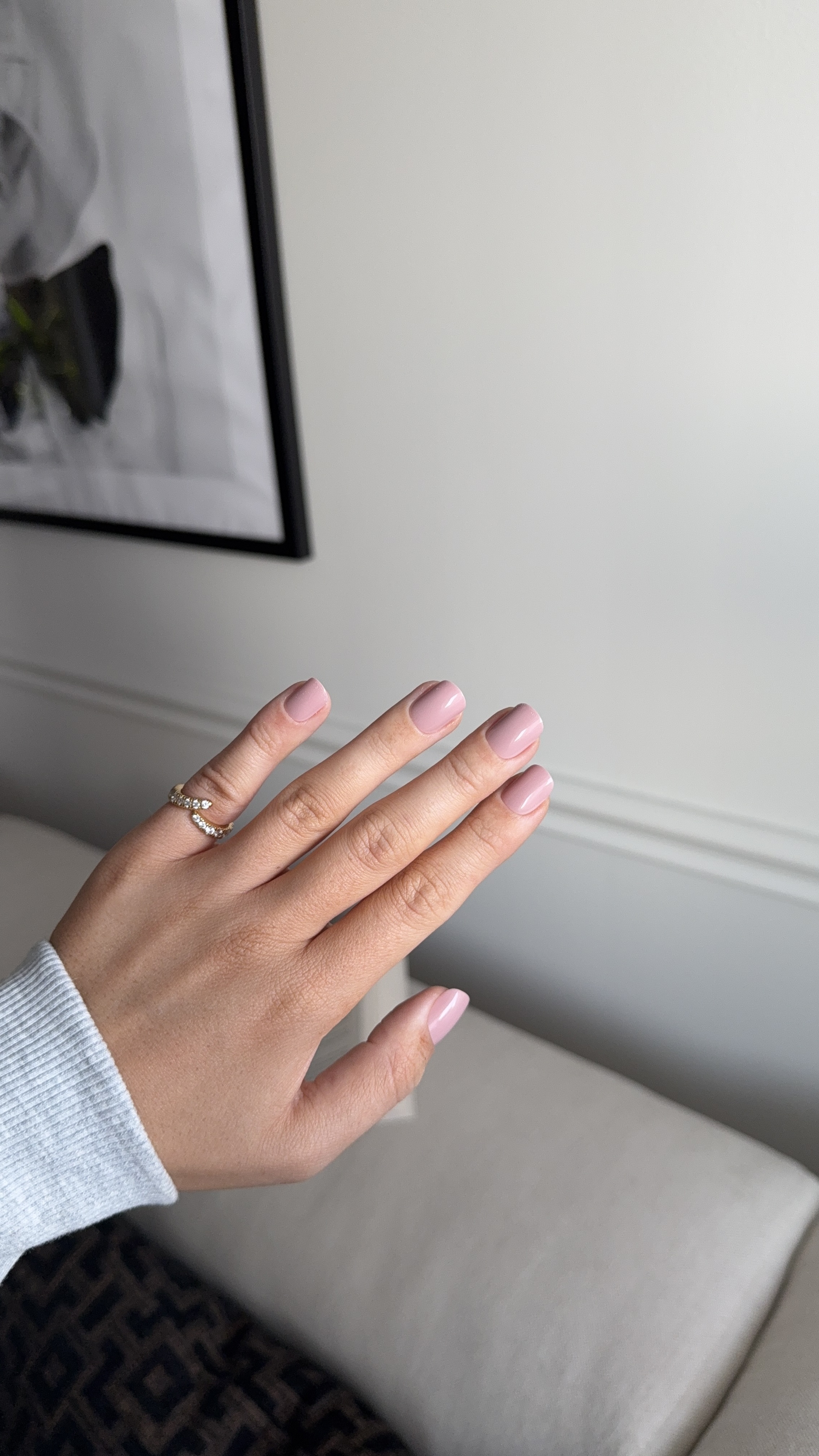 Hand with pink nails and a ring, against a light background.