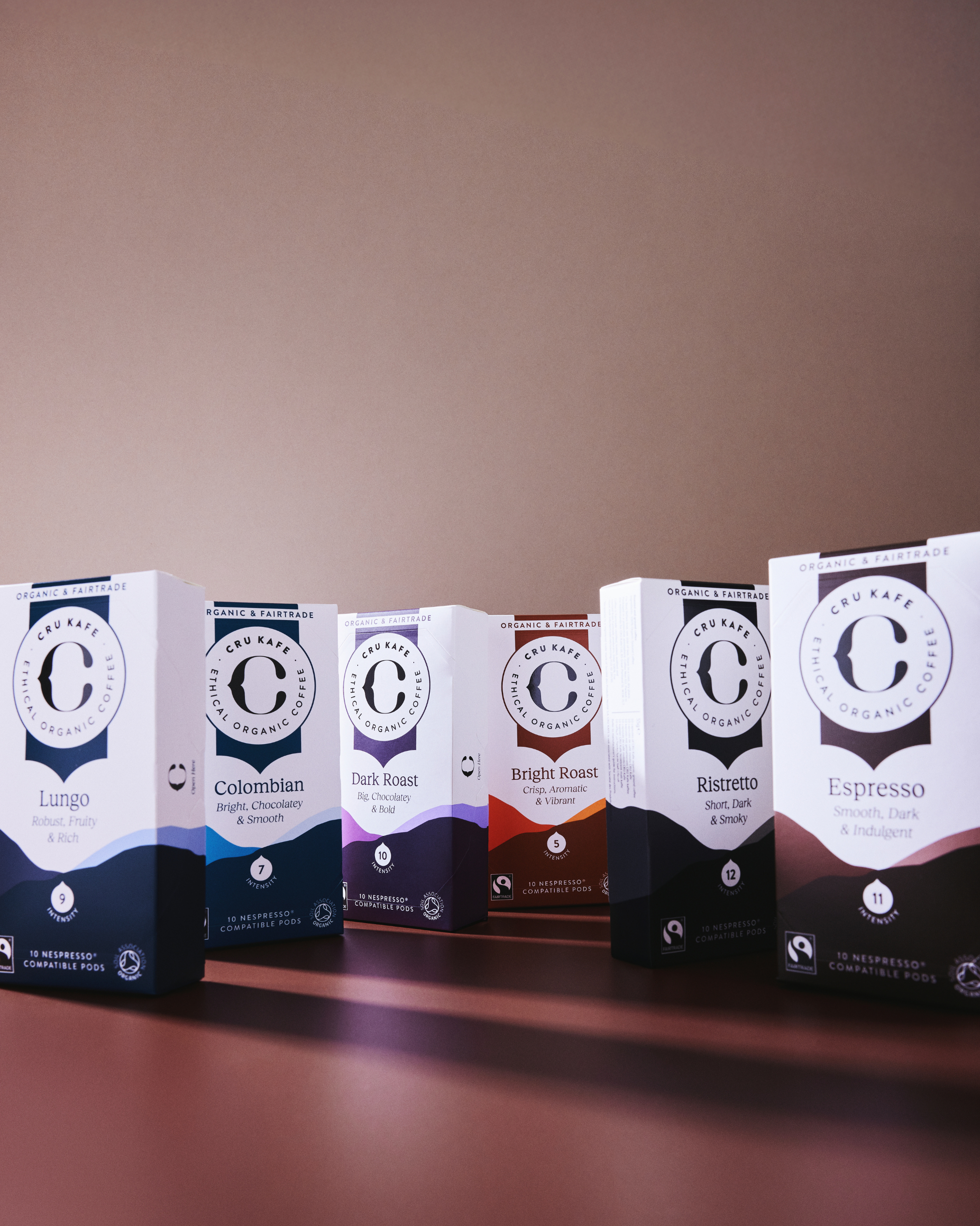 Five boxes of organic coffee pods on a brown background.