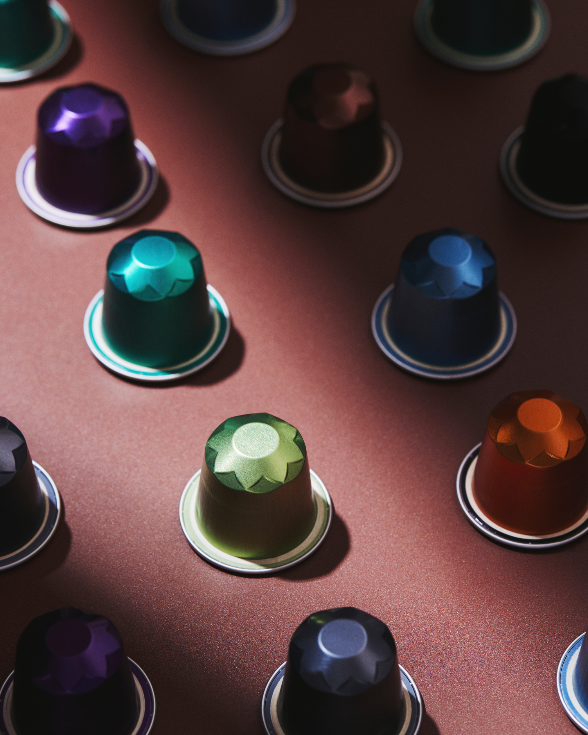 Colored coffee capsules arranged on a brown surface.