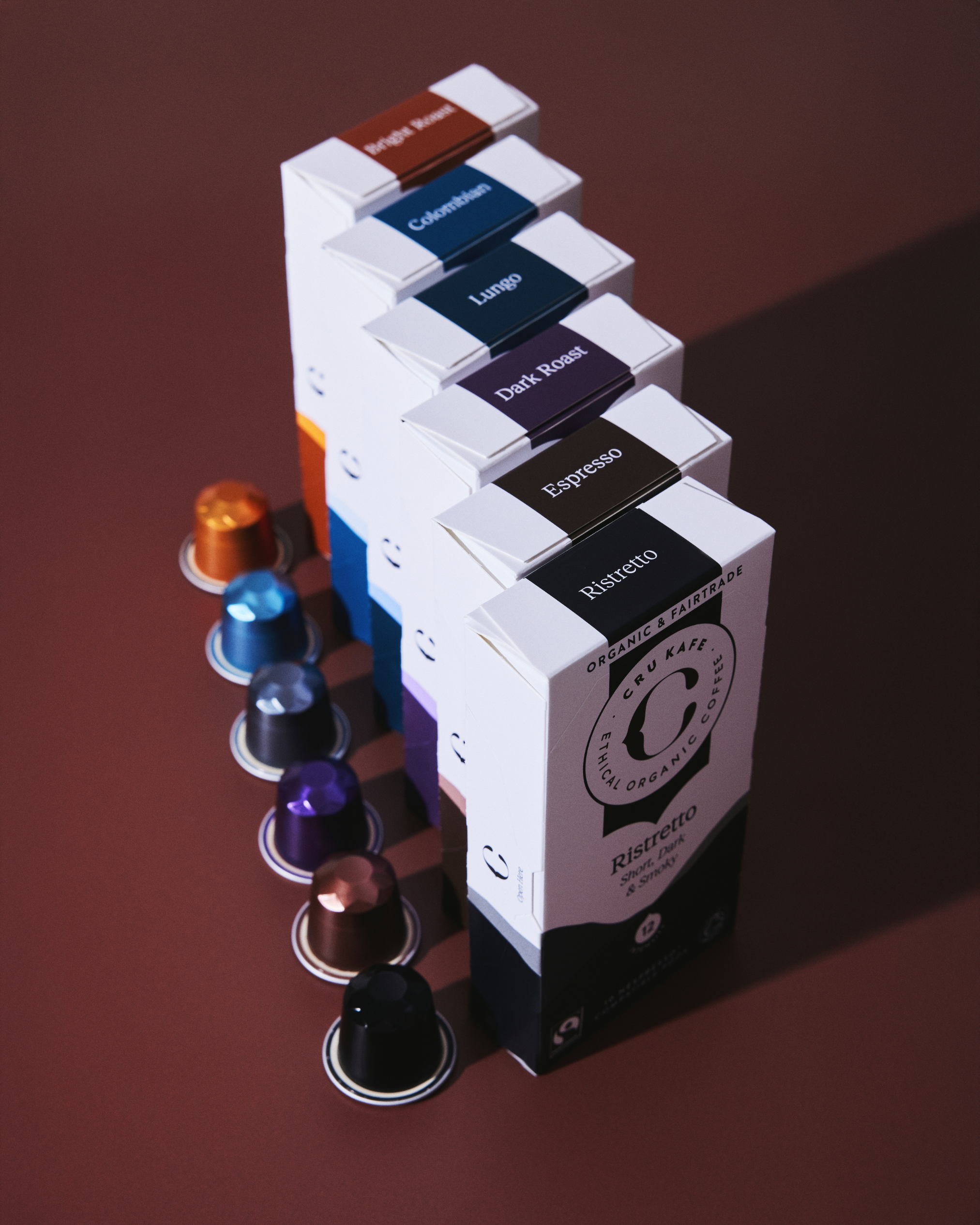 Boxes of coffee pods with matching colored capsules on a brown surface.
