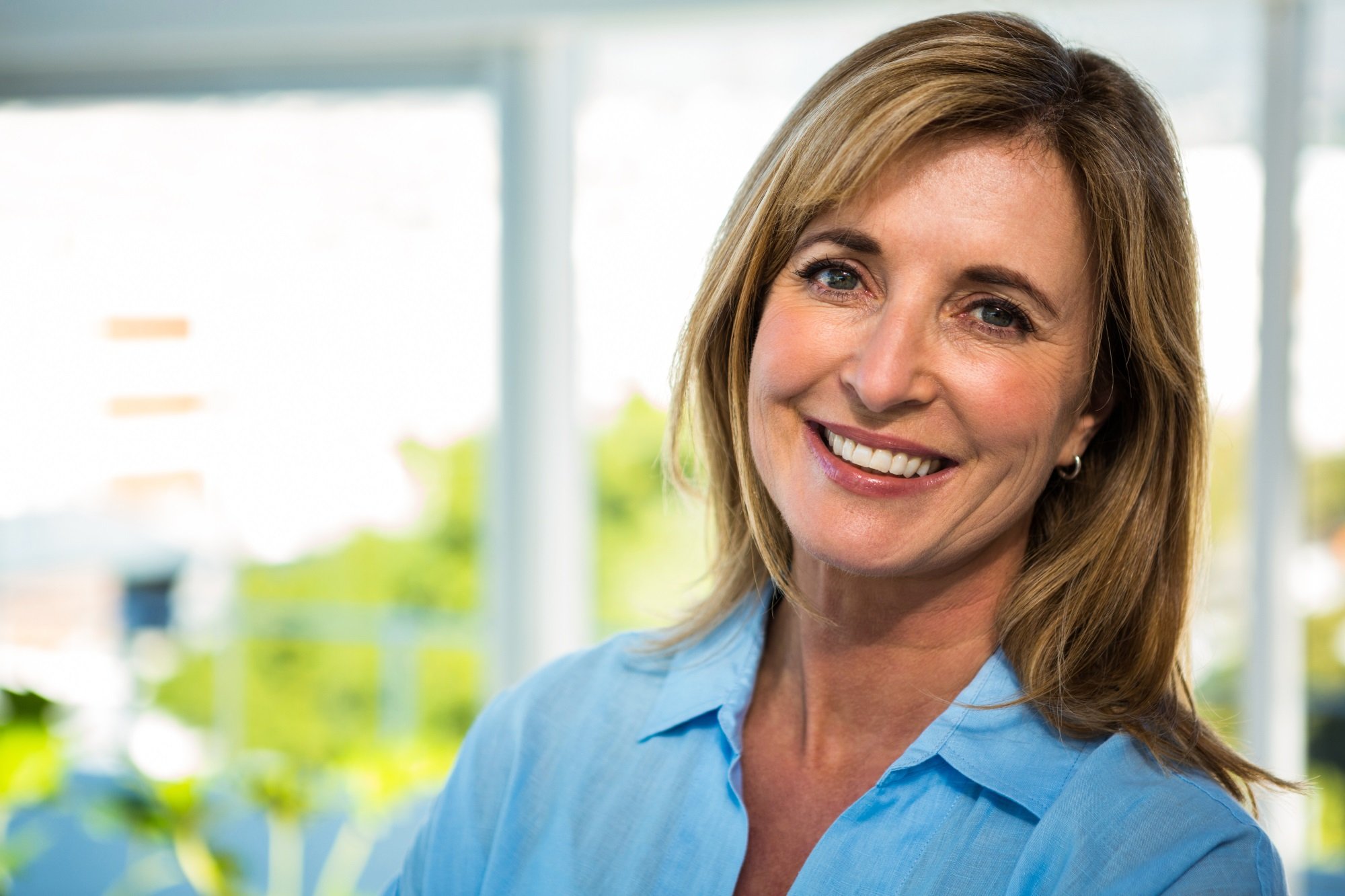 Smiling woman with light brown hair, wearing a blue shirt.