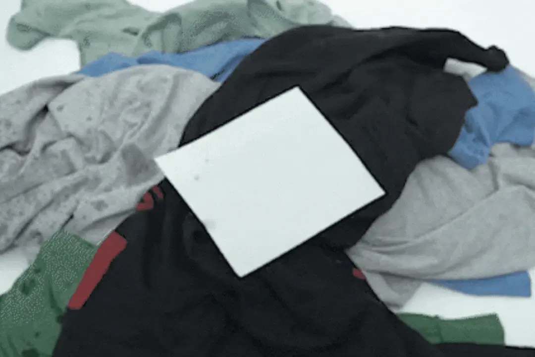 A pile of colorful clothes with a white rectangular object on top.