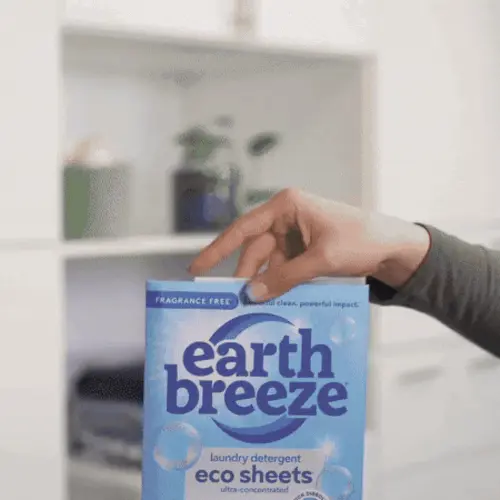 Hand holding a box of Earth Breeze laundry detergent eco sheets.