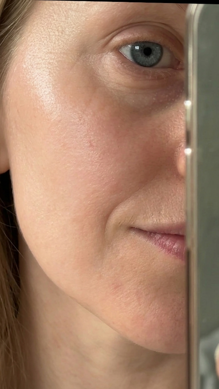 A close-up of a woman's face, showing her blue eye, with half the face obscured by an object.