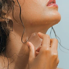 Close-up of a person applying an ice cube to their neck.