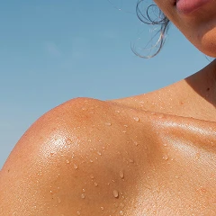 Close-up of a sunlit shoulder with water droplets.