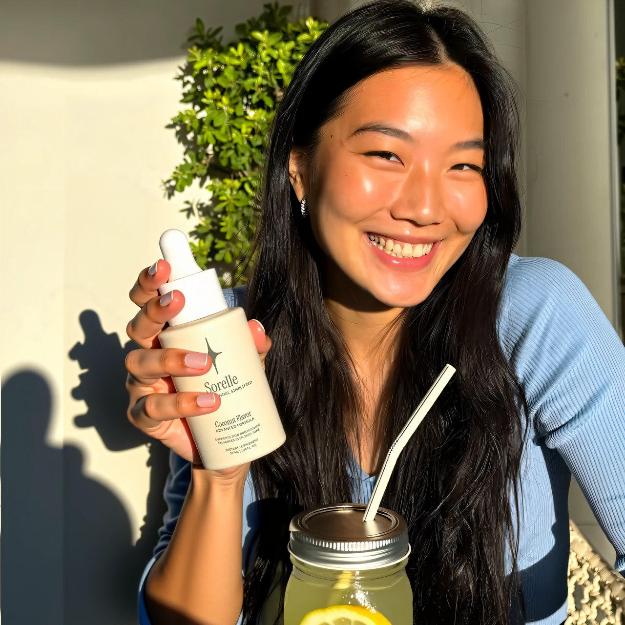 Smiling person holding a skincare product and a jar with a drink.