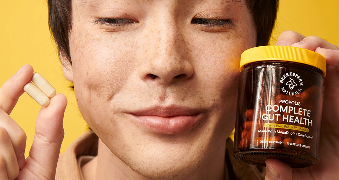 Person holding capsules and a jar labeled 'Complete Gut Health'.
