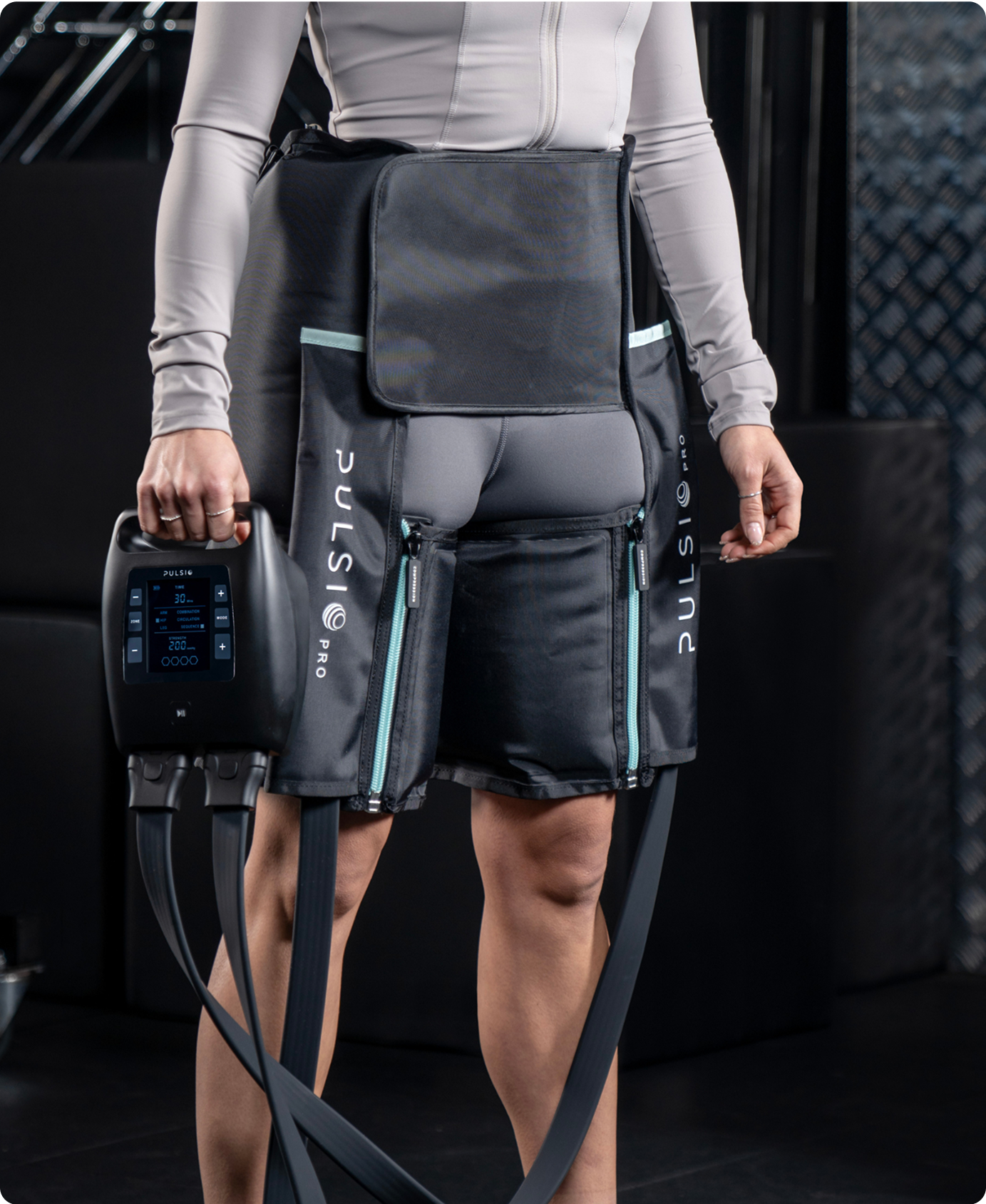 Person wearing a compression therapy device with control unit and tubes.