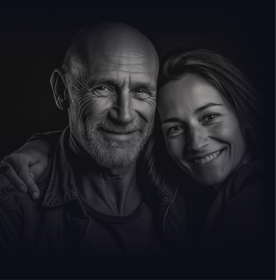 A black and white portrait of a smiling older man and a younger woman.