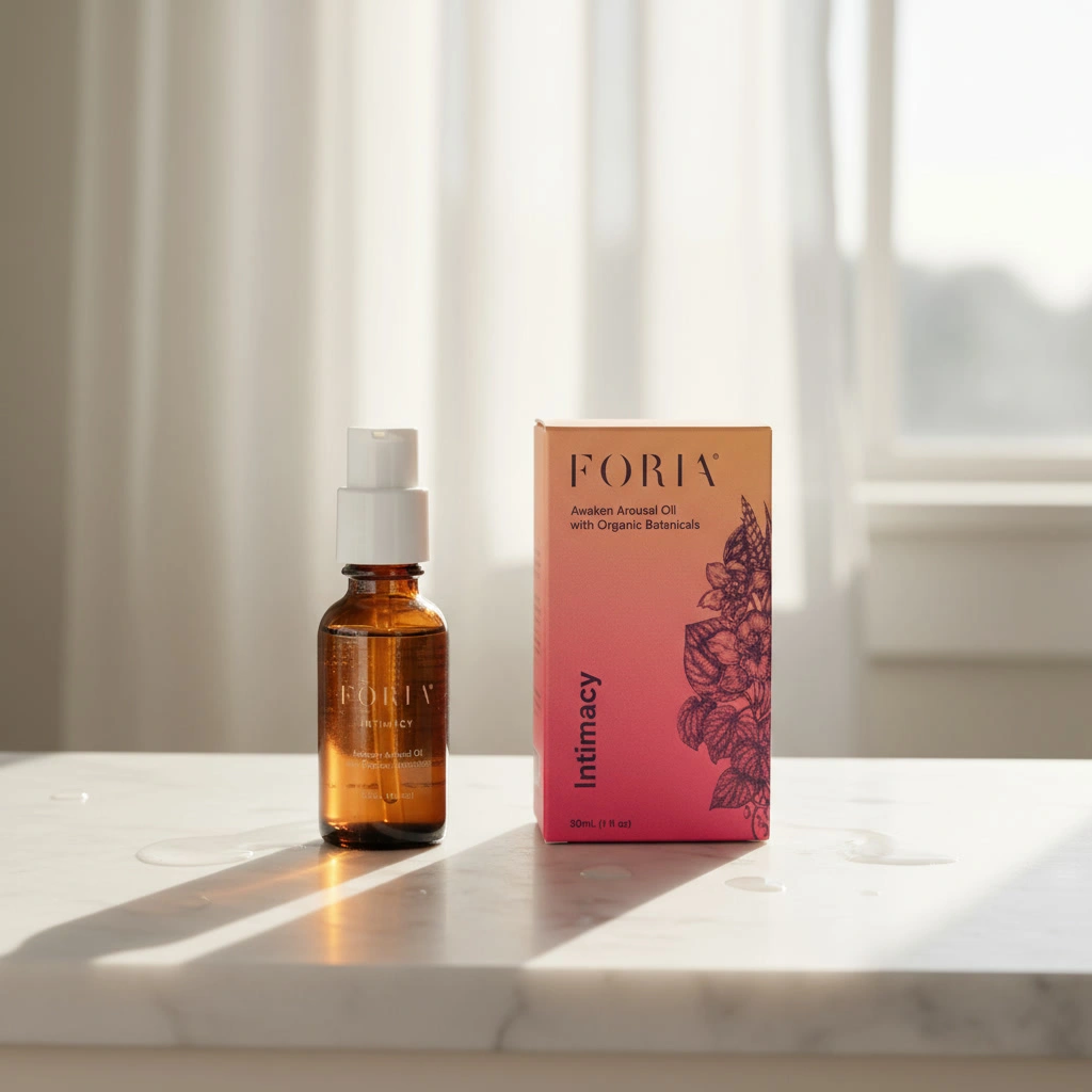 A bottle and box of Foria intimacy oil on a sunlit table.