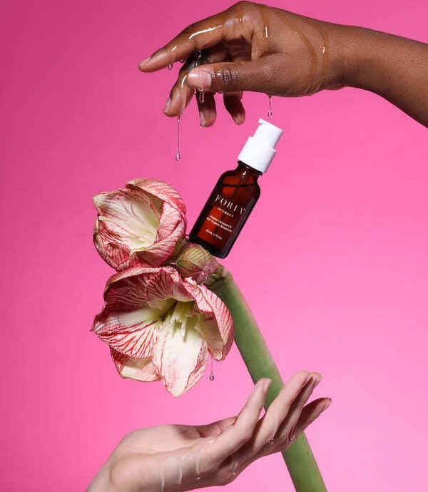 Two people using a dropper to apply oil on skin.