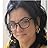 A low-resolution headshot of a woman with dark hair and glasses looking slightly to her right.