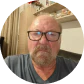 A close-up photo of a man with glasses and a beard.