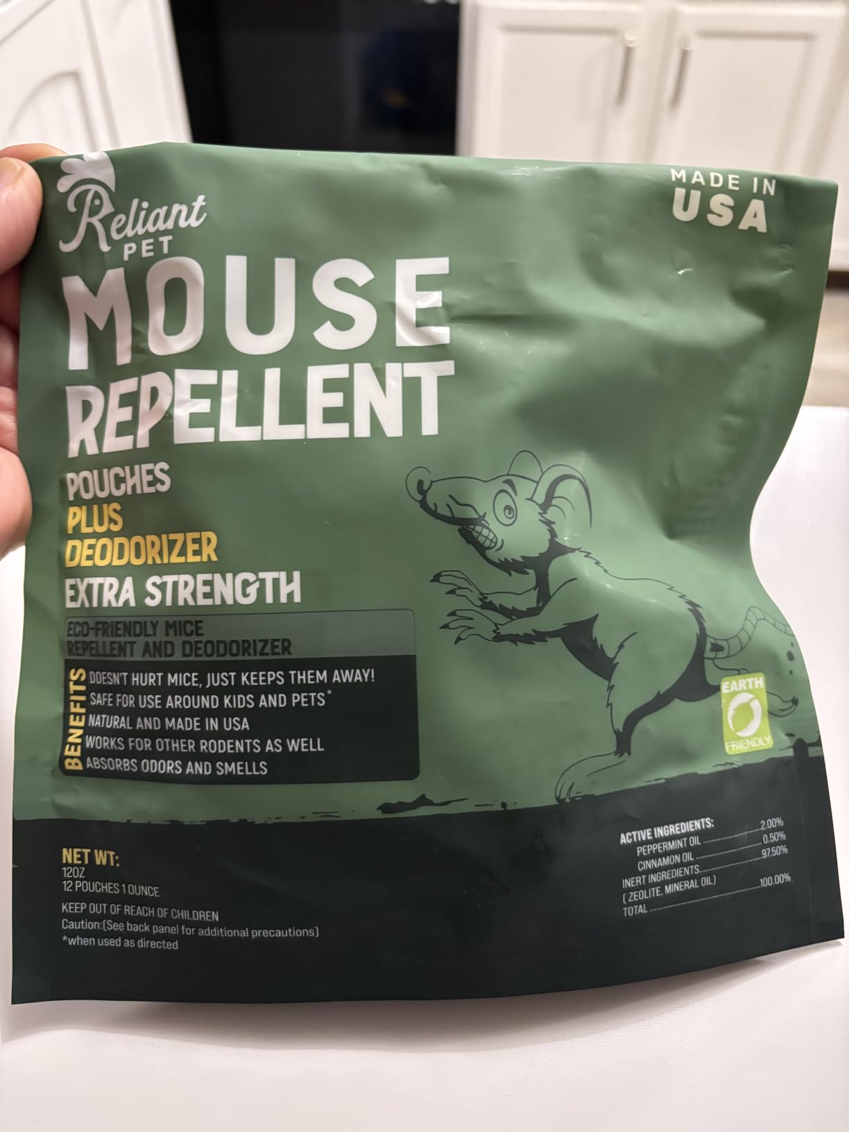 A hand holding a green bag of Reliant Pet Mouse Repellent pouches.