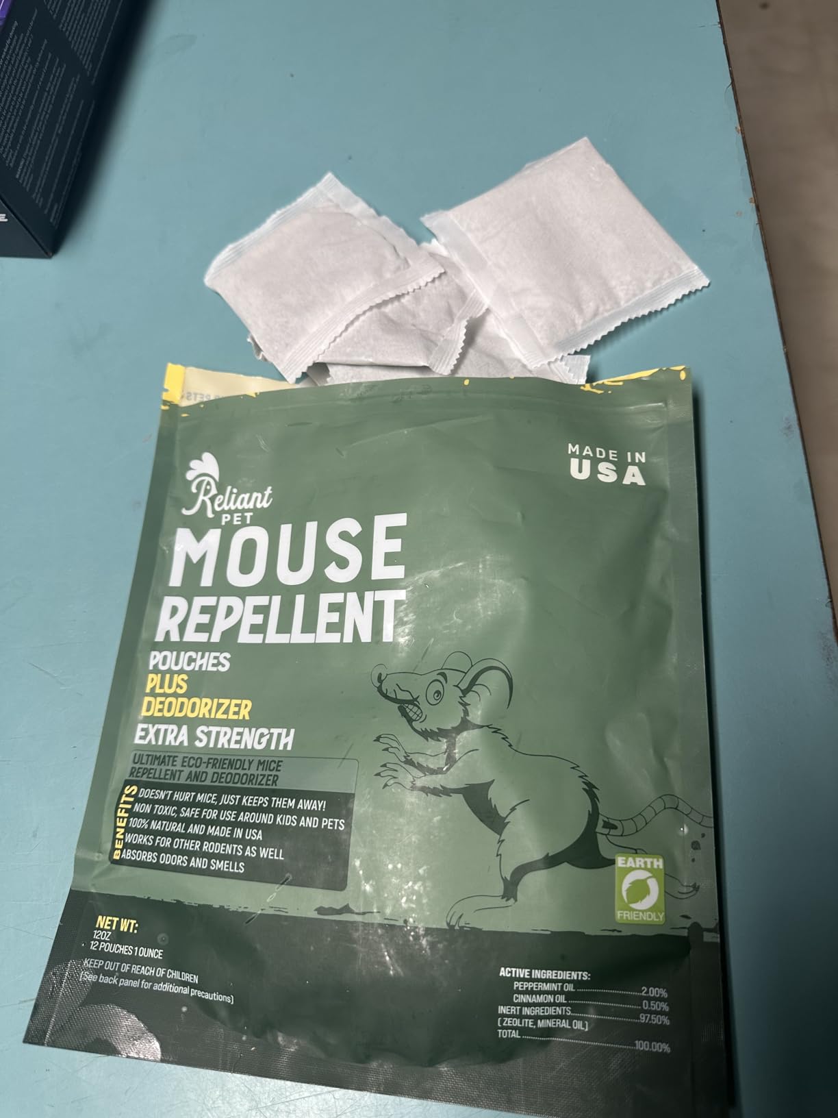 A green bag of Reliant Pet Mouse Repellent with several white pouches spilling out of the top.