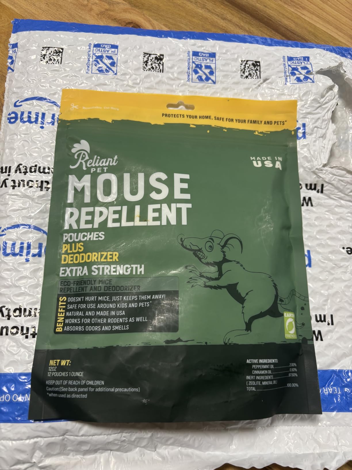 A green pouch of Reliant Pet Mouse Repellent sits on top of a white bubble mailer.