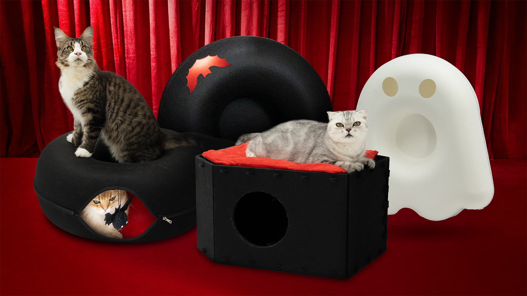 Two cats on plush structures with a red curtain background.