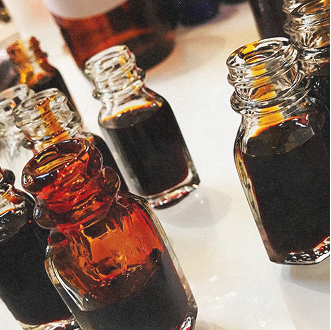 Several small glass bottles filled with dark liquid on a white surface.