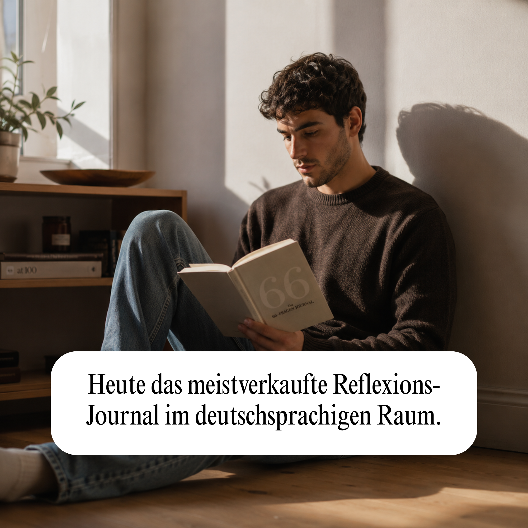 A young man with dark curly hair sits on the floor, reading a journal in a sunlit room.