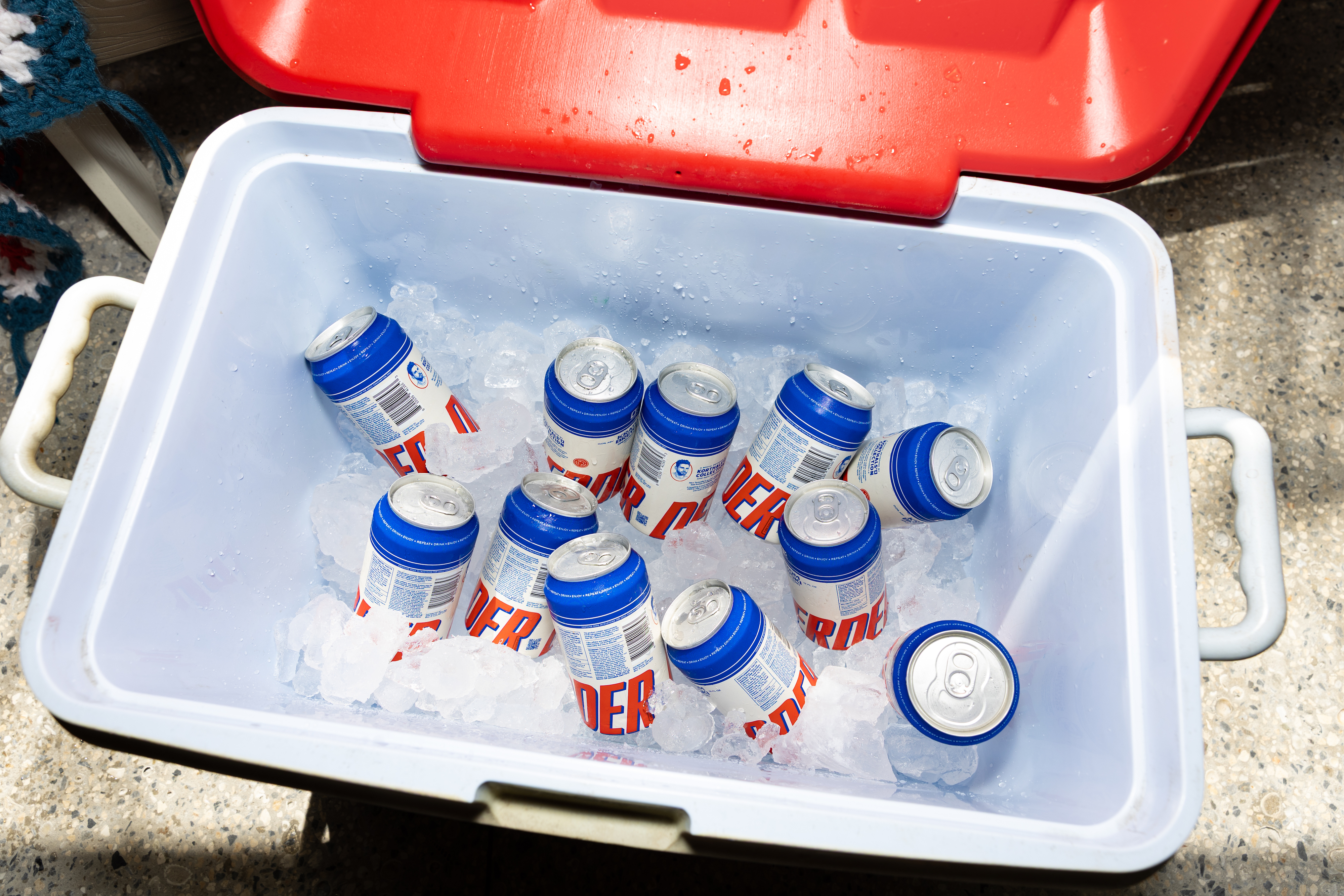 Cans with blue lids in a cooler filled with ice.