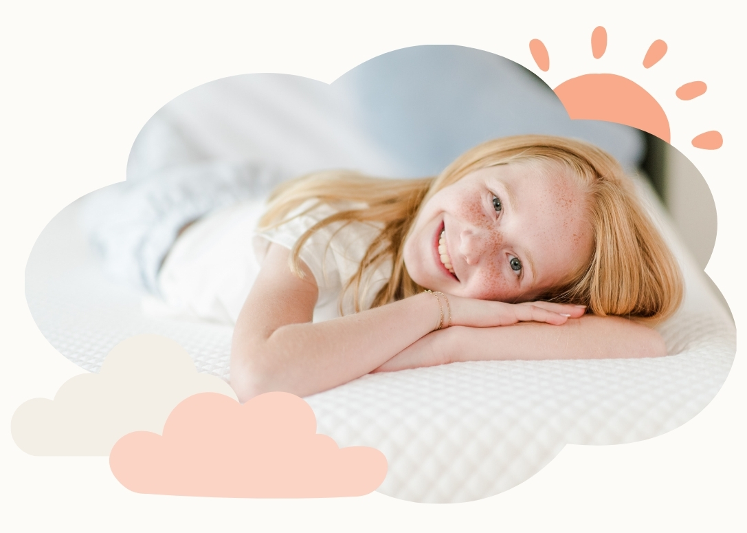 A child laying on a white mattress with their head resting on their folded arms. Light pink decorative shapes are around the image including a sun and clouds.