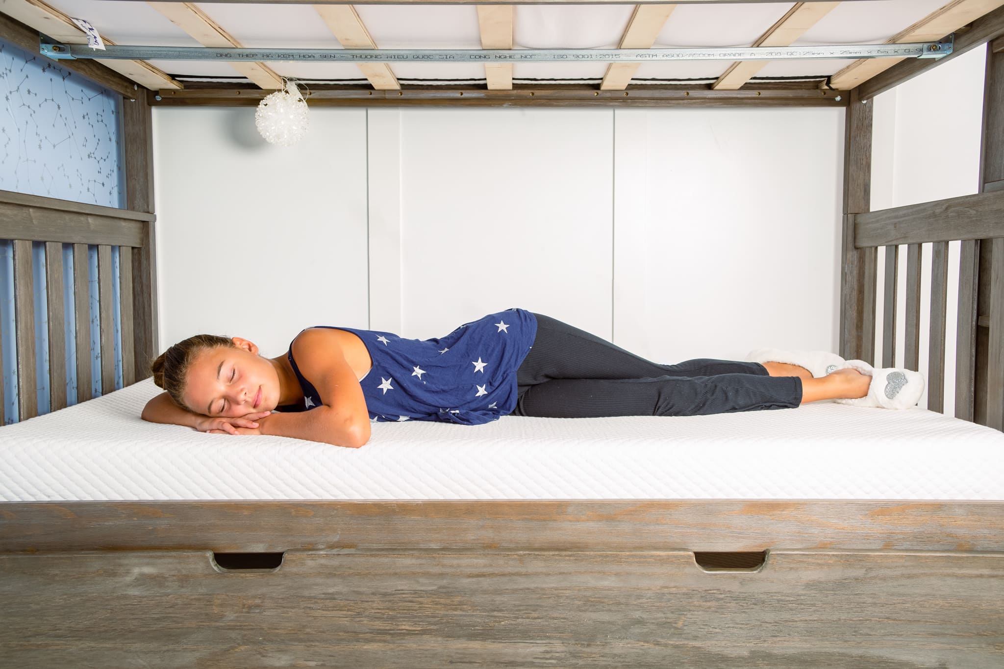 Little girl sleeping peacefully on a clean, white mattress.