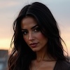 Person with long dark hair against a sunset background.