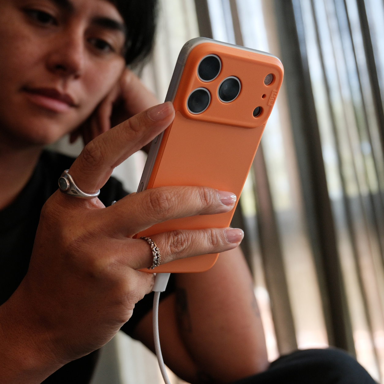 A person holding a charging smartphone in an orange case.