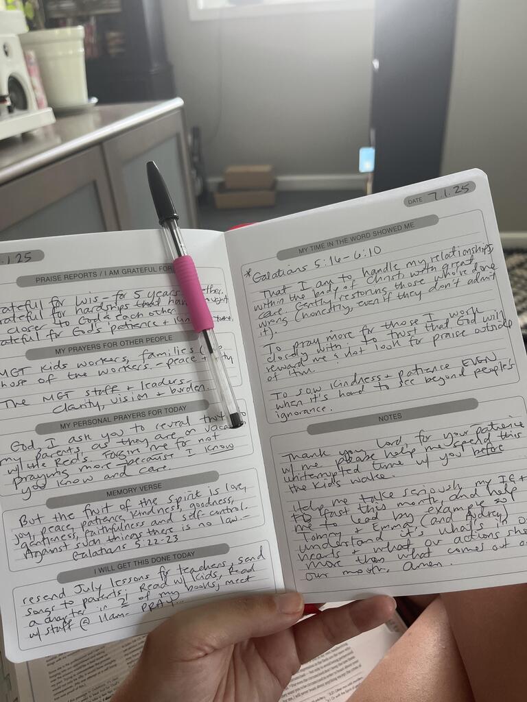 Open journal with handwritten notes and a pen resting on a page.