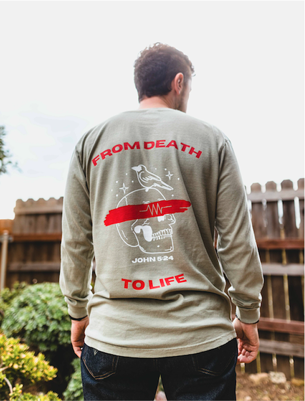 Person wearing a shirt with skull, bird, and 'From Death to Life' printed on back.