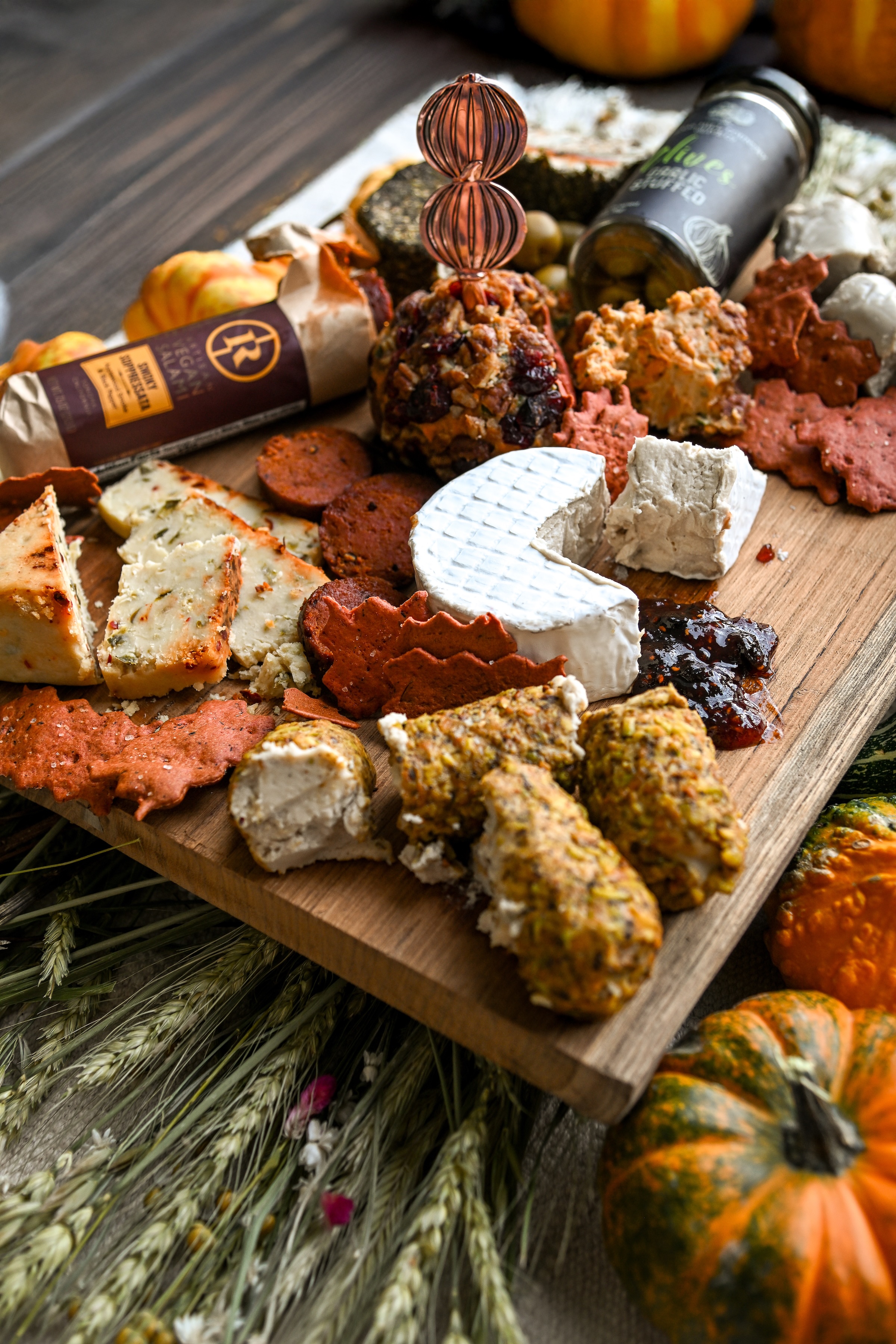 A wooden board with assorted cheeses, crackers, and condiments.