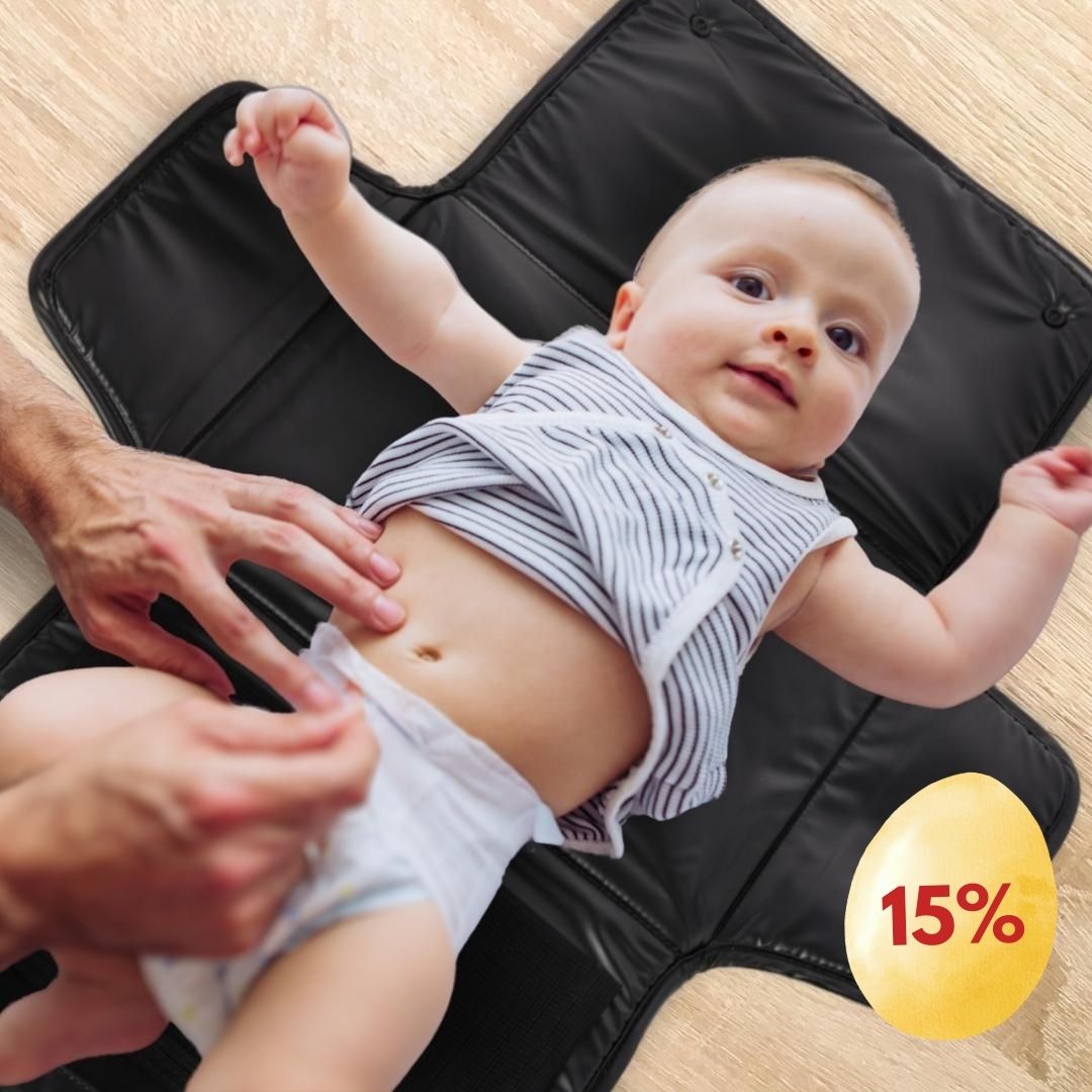 Baby lying on a black changing mat, with a 15% discount symbol.