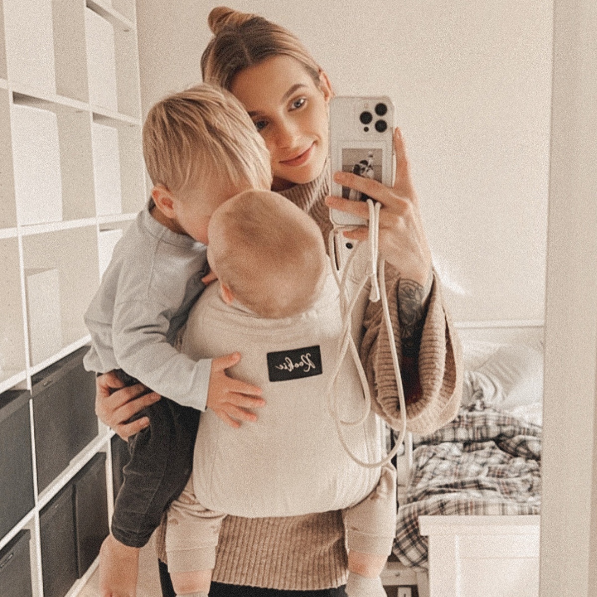 Person taking a mirror selfie with two young children.