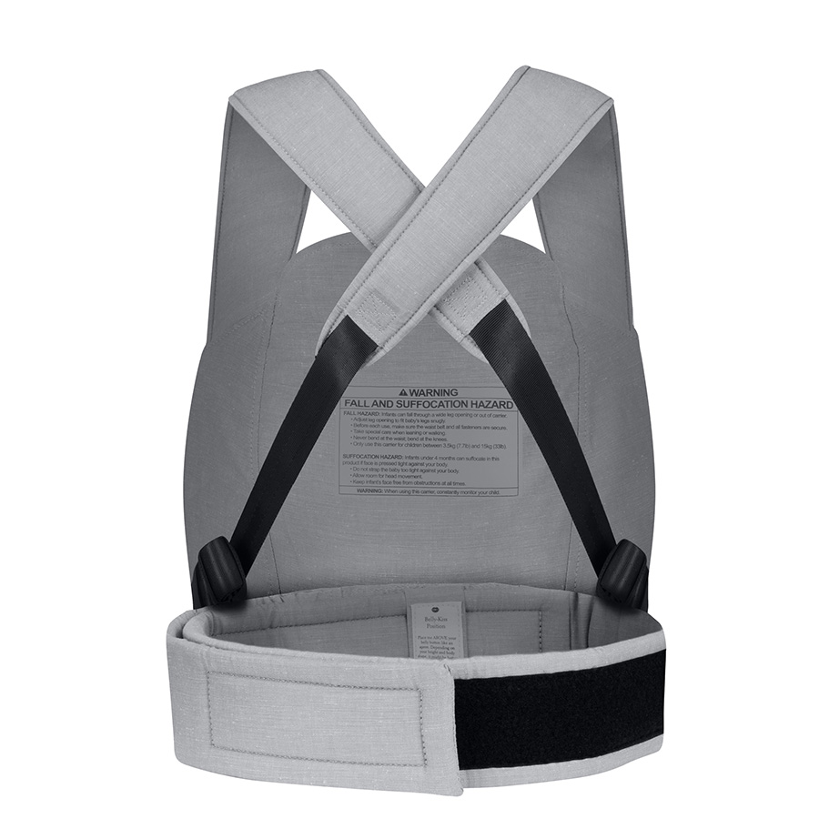 The back view of a light gray, soft-structured baby carrier with crossed shoulder straps and a warning label.