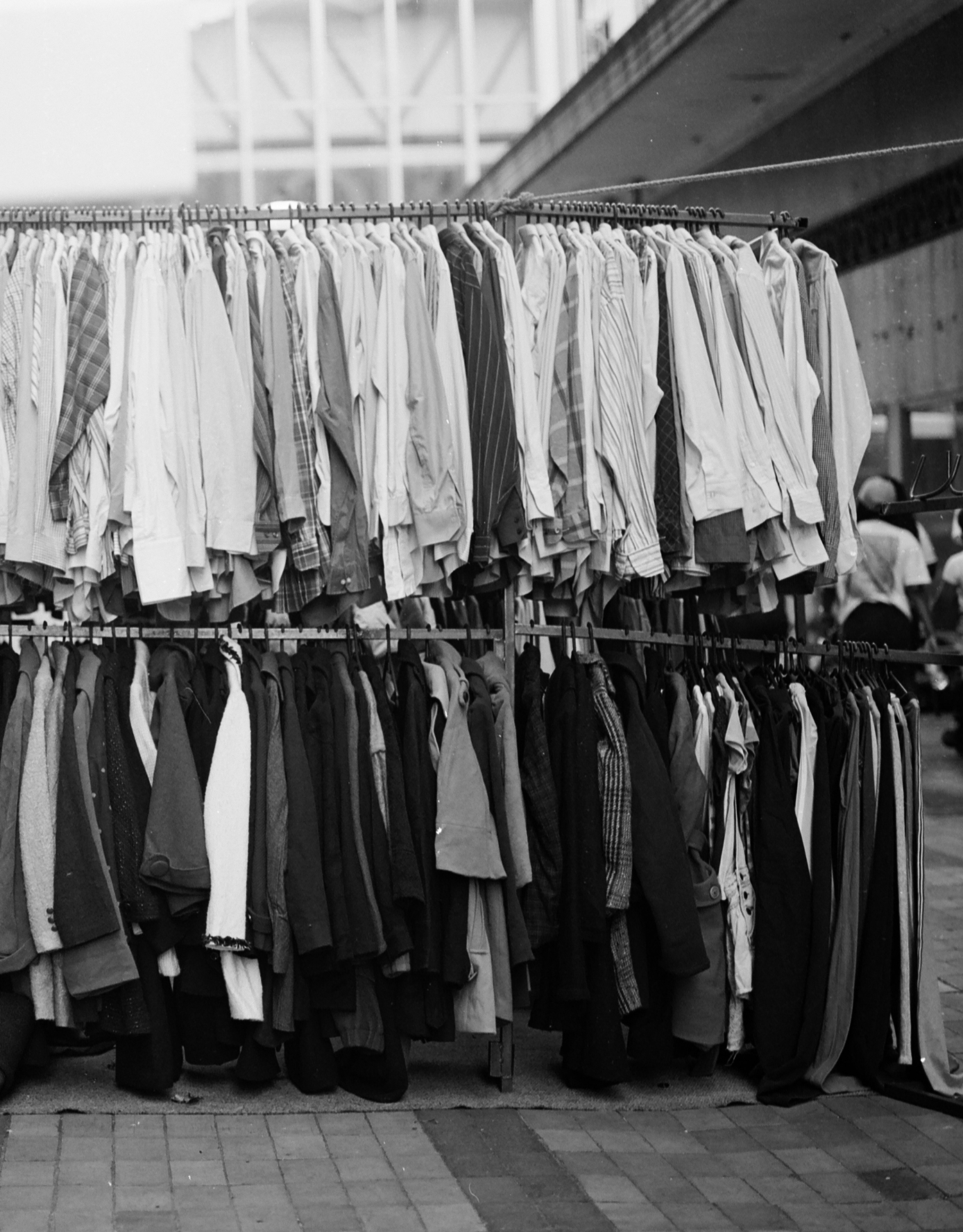 Black and white photo of clothes hanging on a rack outdoors.